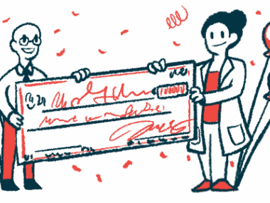 Two people each hold a side of a giant check amid balloons and confetti.