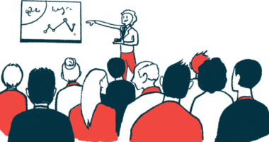 A person points to a screen on a wall while making a presentation to a crowd.