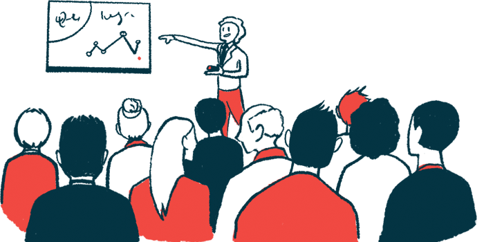 A person points to a screen on a wall while making a presentation to a crowd.